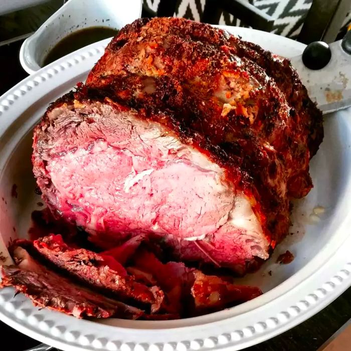 Prime rib with a perfectly pink, juicy center served on a classic white ceramic dish