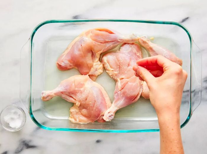 Chicken slices seasoned and resting in a baking dish