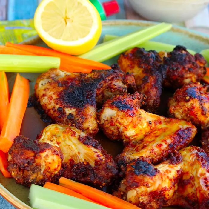 A high-angle view of harissa and lemon-pepper wings, served with celery and carrots on the side