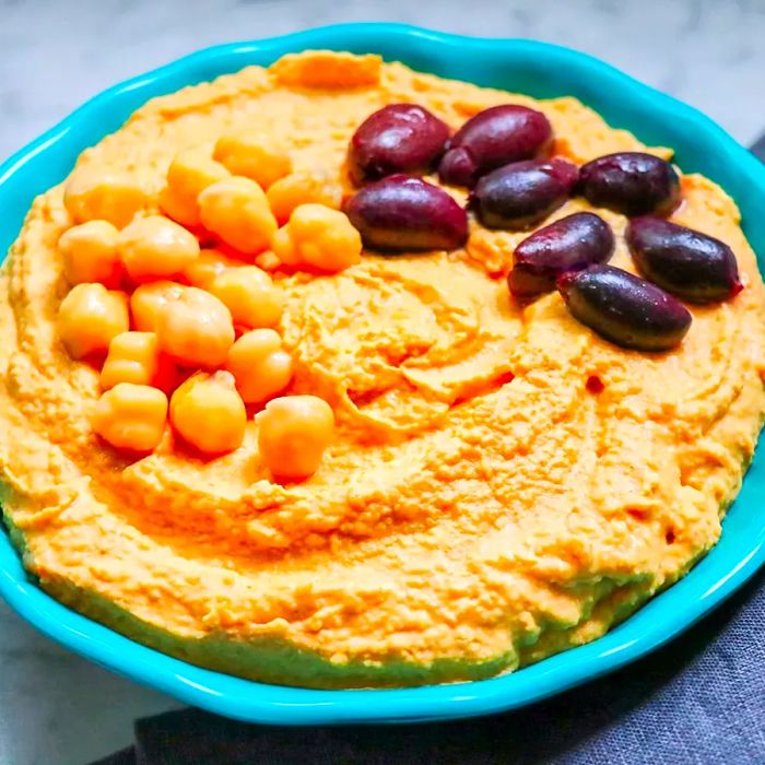 A high-angle view of a bowl filled with smooth harissa hummus