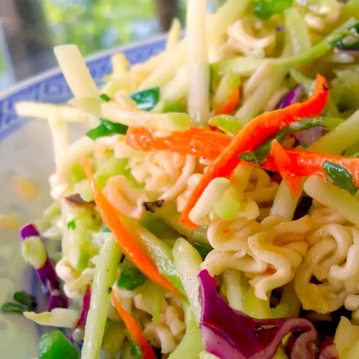 A bowl of ramen noodles mixed with shredded broccoli in a salad