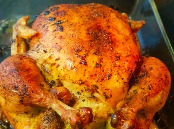 A close-up of dry brined roasted chicken in a roasting pan.