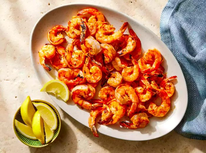 A plate of fiery grilled shrimp served with lemon wedges