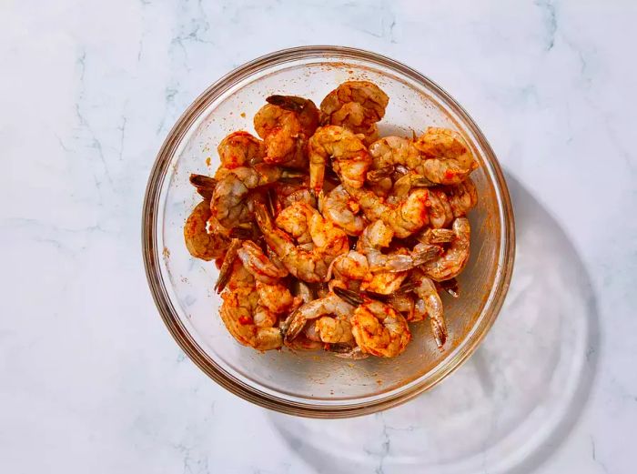 A glass bowl with shrimp evenly coated in spicy garlic sauce