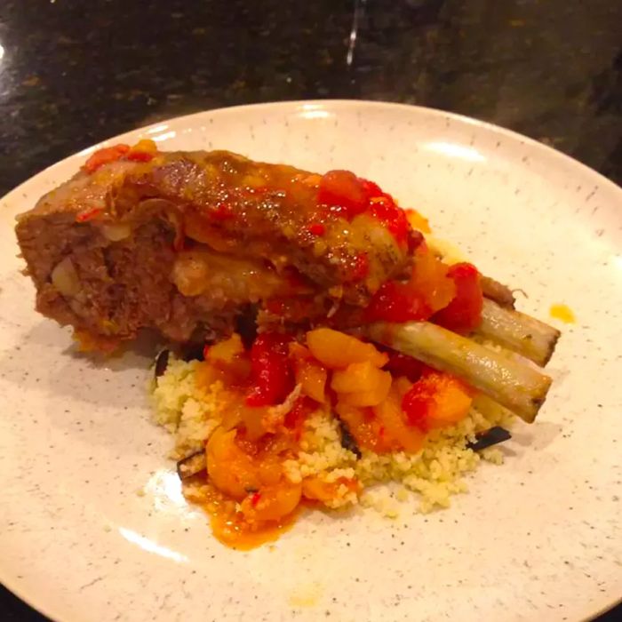 A view of a plate featuring Moroccan-style lamb shanks served with apricots