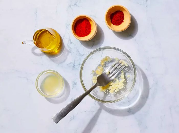 A small glass bowl filled with crushed garlic and a fork