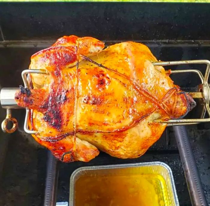 Chicken cooking on a rotisserie over a grill