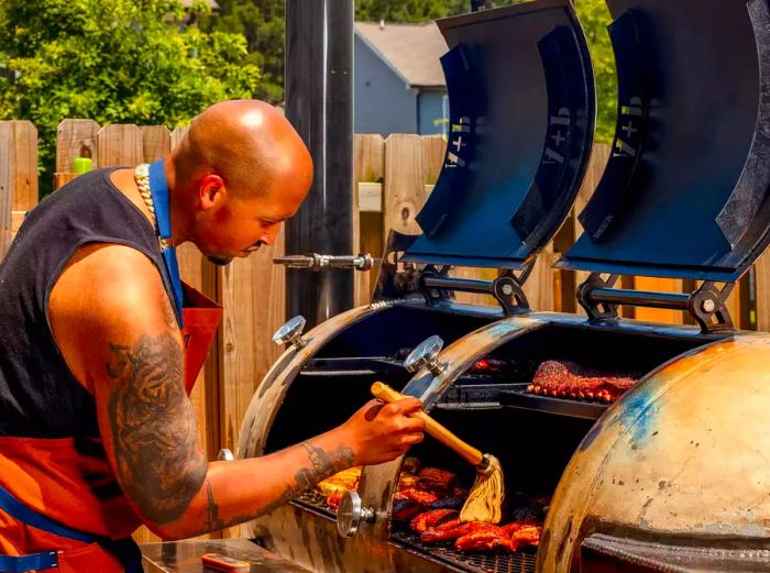 Dakari Akorede tending to some ribs on his custom grill in the backyard of his Atlanta home.