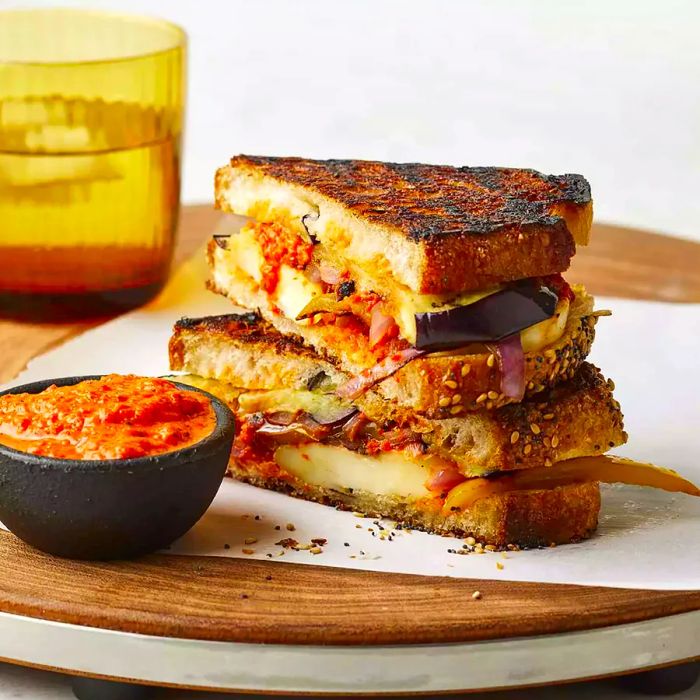 A close-up of a harissa-spiced fried halloumi panini, cut in half and stacked on top of another sandwich