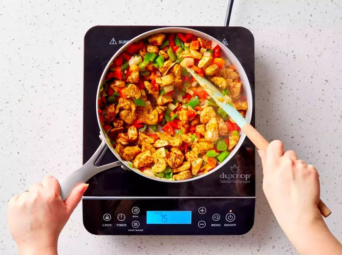 Chicken and vegetables cooking in a skillet until the veggies are tender