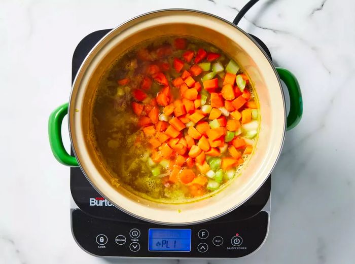 Carrots, celery, and potatoes added to the pot.