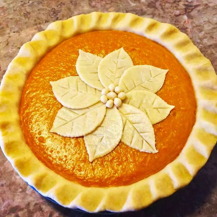 A close-up of sweet potato pies with intricately designed flower crusts.