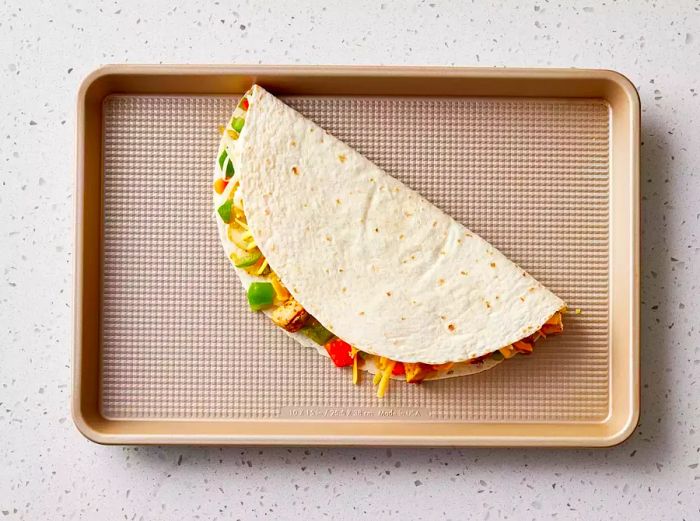 Tortilla folded over and placed on a baking sheet