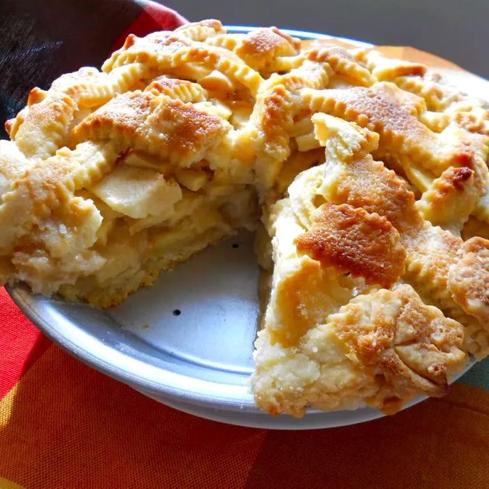 A perfectly baked apple pie with a golden lattice crust and a slice missing, showing off its delicious filling.