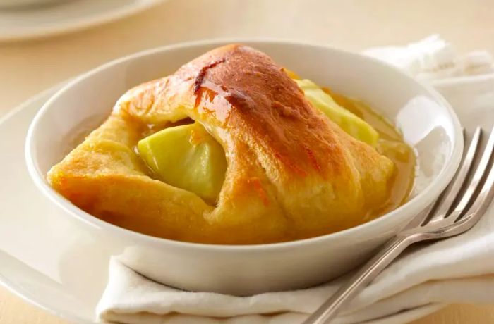 Apple wedges wrapped in pastry dough and baked with a sweet sauce make for a delicious apple dumpling.