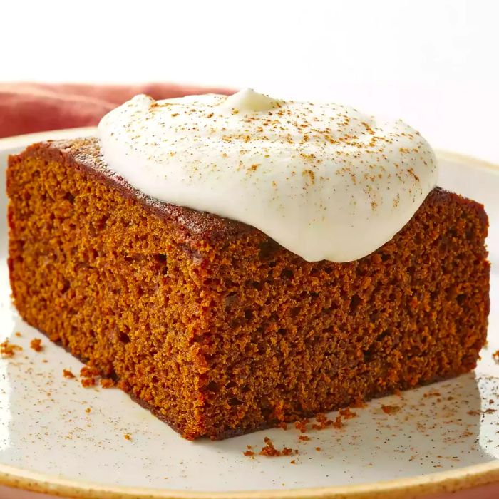 a low-angle view of a slice of gingerbread topped with a dollop of whipped cream