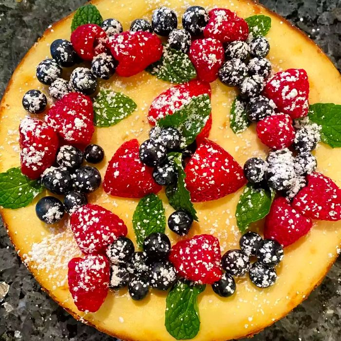 Aerial shot of Chantal's New York Cheesecake topped with fresh strawberries, raspberries, blueberries, and mint leaves