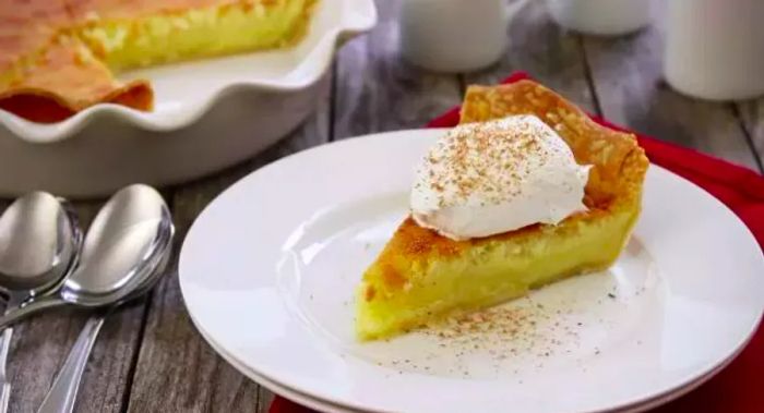 A slice of buttermilk pie topped with whipped cream.