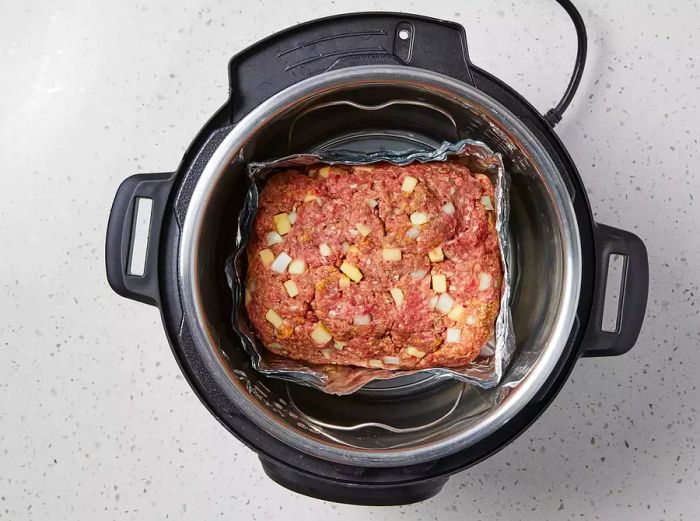 Place the meatloaf in the pressure cooker with half a cup of water underneath.