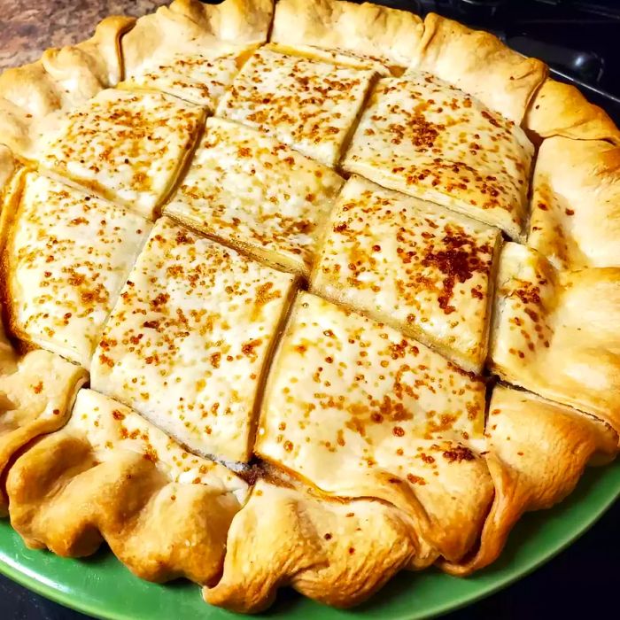 A slice of Fresh Pear Pie served on a green dish.