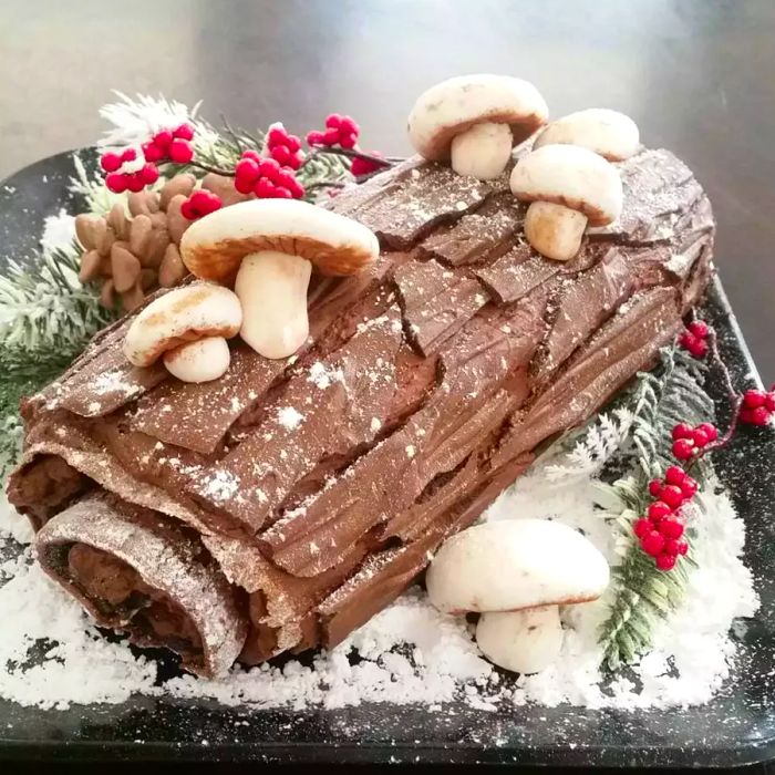 a rich, rolled cake decorated to resemble a log, complete with chocolate 'bark', meringue mushrooms, and a dusting of powdered sugar snow