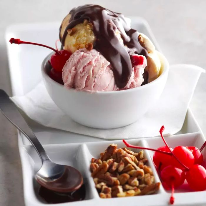 Scoops of ice cream topped with warm hot fudge, nuts, and cherries, creating the perfect hot fudge sundae