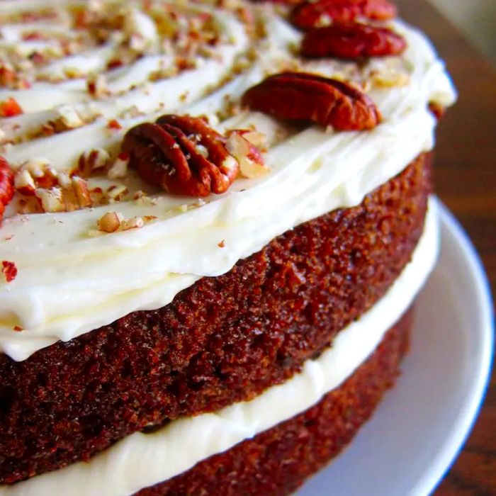 a moist carrot cake topped with generous layers of frosting and a sprinkle of pecans