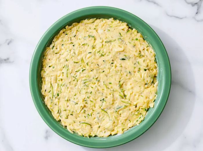 The zucchini mixture is spread evenly in the prepared pie dish.