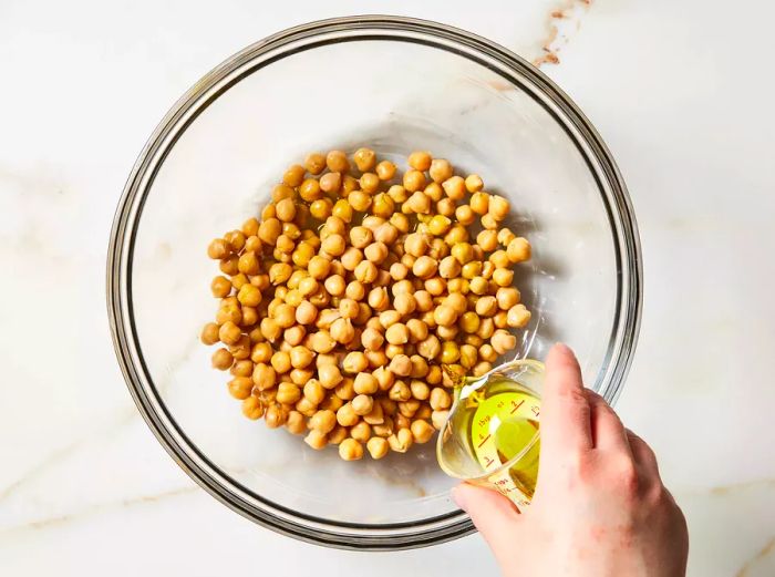 Olive oil drizzled over a bowl of chickpeas.