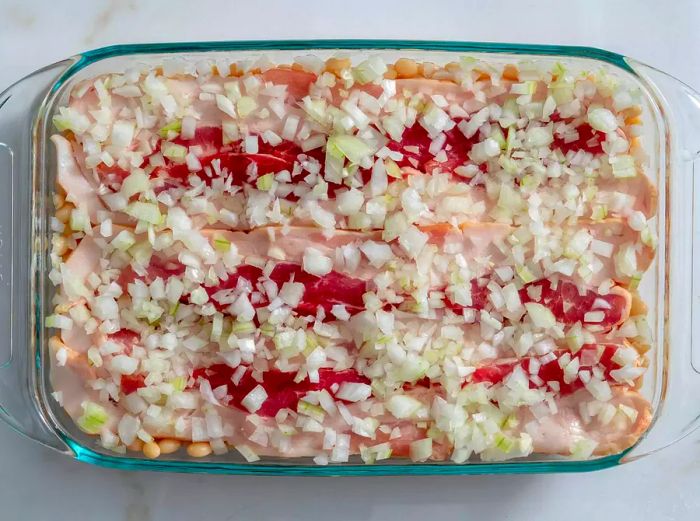 Aerial view of a baking dish layered with beans, bacon, and onions, ready for Boston baked beans