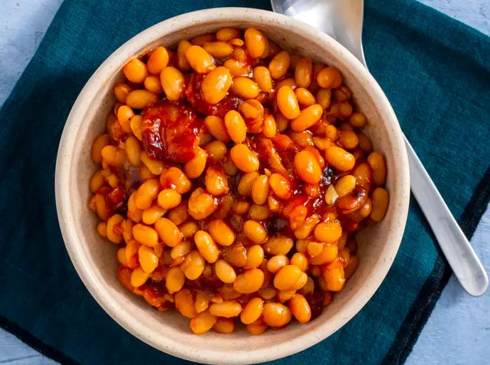 An aerial view of Boston baked beans served in a bowl, placed on top of a kitchen towel