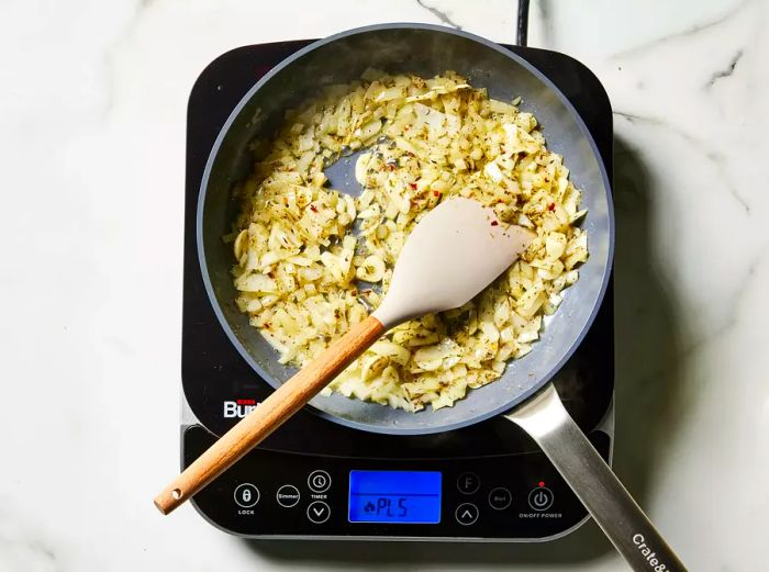 Cooking garlic, onions, and seasonings in a skillet