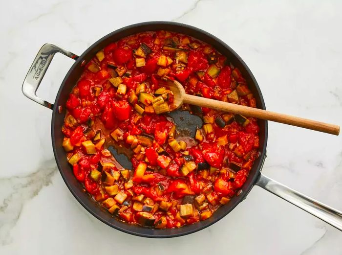 Overhead view of tomatoes and eggplant simmering together in a pan