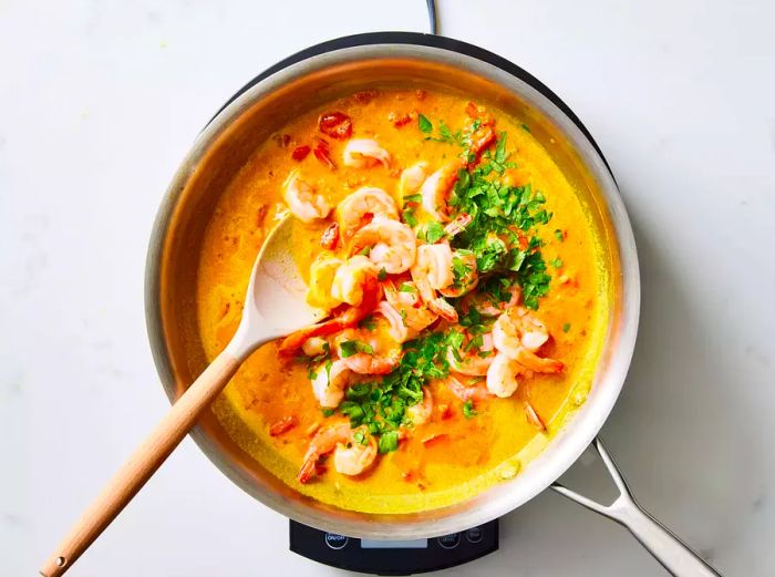 A pan of Indian shrimp curry topped with fresh cilantro