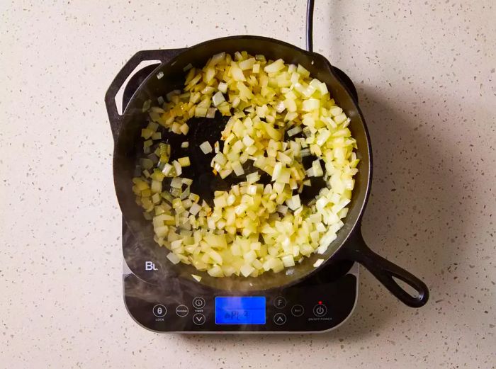 Onions being sautéed in a cast iron skillet on a stovetop