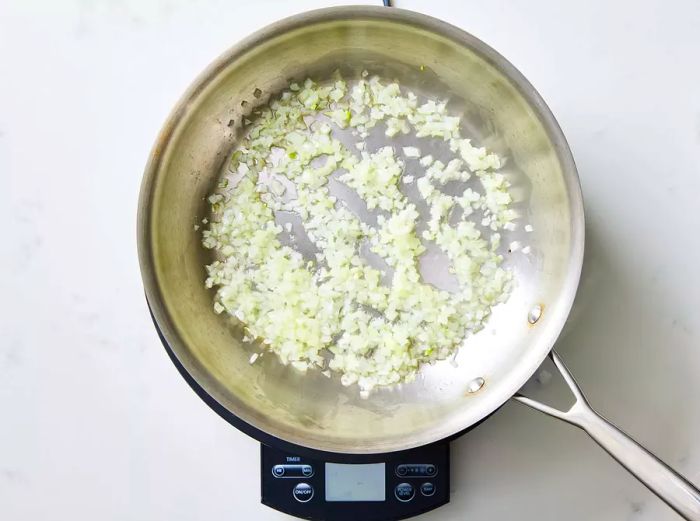 A skillet with onions sautéing in peanut oil