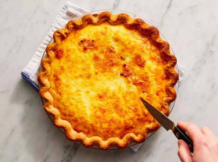 Quiche baked to a golden-brown perfection, with a knife inserted coming out clean.