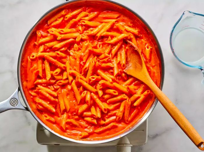 A pan of penne pasta coated in creamy tomato sauce