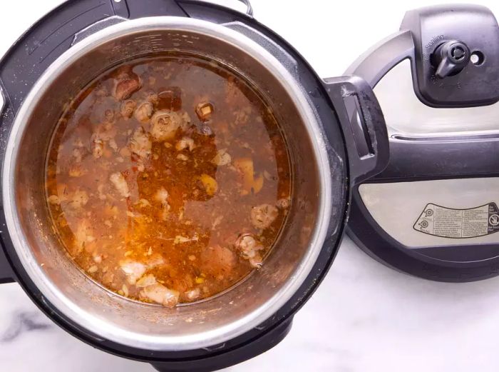 An opened Instant Pot with beef, mushrooms, and broth inside