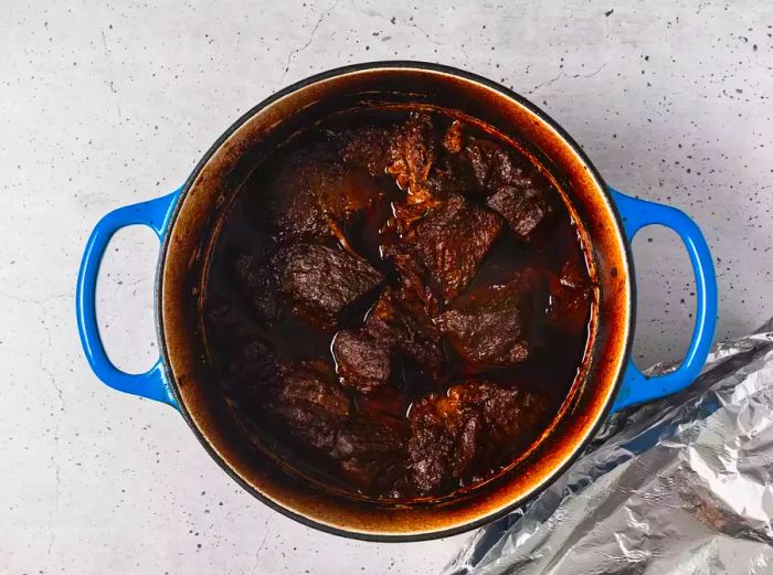 A pot with baked beef simmering in chili sauce