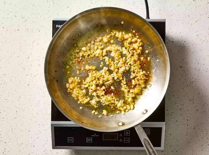 Shallots and garlic cooking in the skillet until they become tender and translucent.