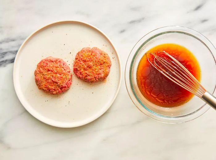 Seasoned patties set aside, with the beef stock mixture prepared and waiting in the bowl.