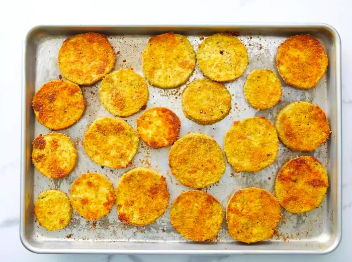 Breadcrumb-coated eggplant slices arranged on a baking sheet