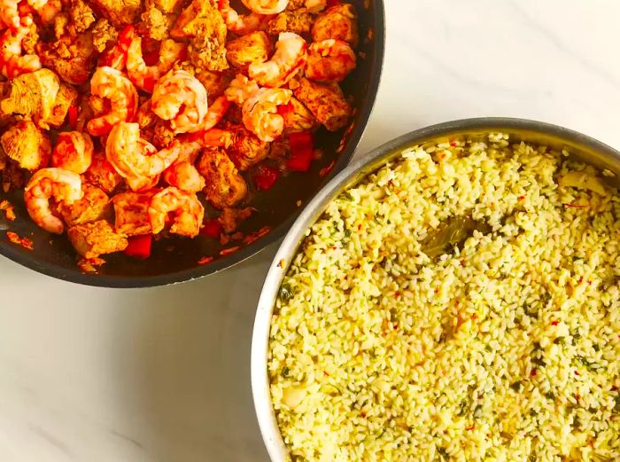 One pan with cooked shrimp and chicken, another with rice