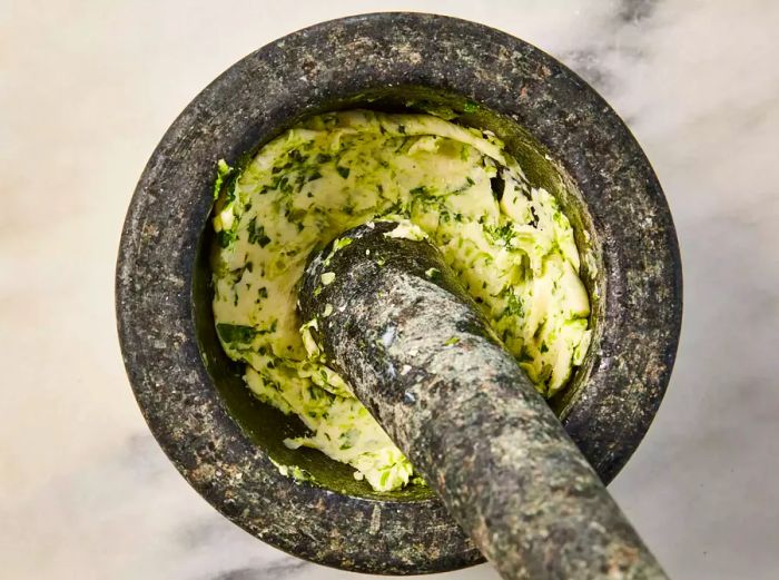 A mortar and pestle with garlic-herb butter