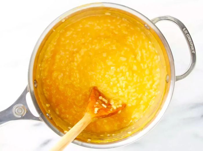 An overhead view of butternut squash risotto cooking in a saucepan.