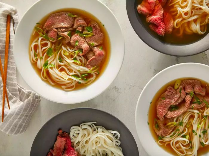 Distribute the noodles into four bowls, adding sirloin, cilantro, and green onions. Ladle the hot broth over the top and let it sit for a moment.