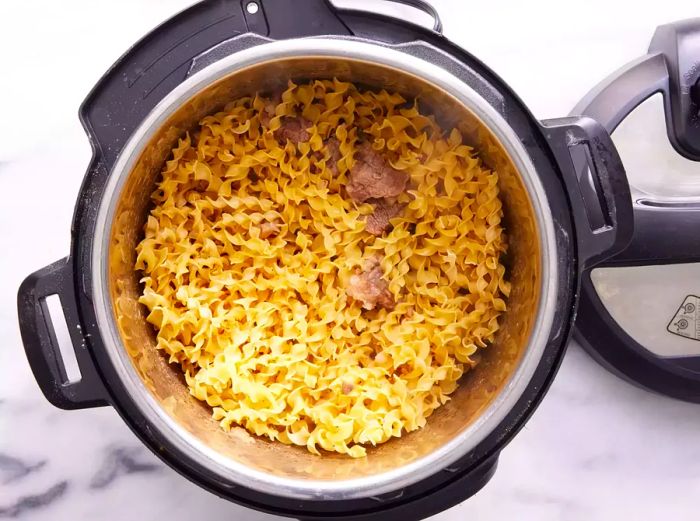 An Instant Pot with egg noodles mixed in with the beef and mushroom mixture