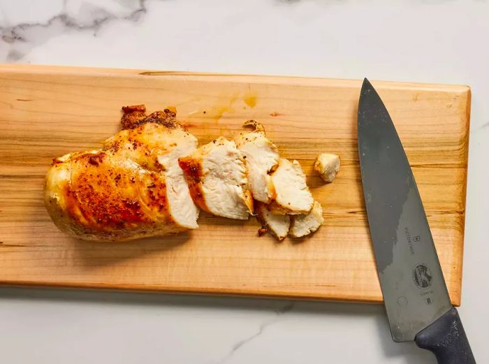 A cutting board with a chicken breast sliced into pieces