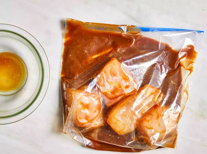 A bird's-eye view of Chilean sea bass soaking in marinade inside a ziplock bag.